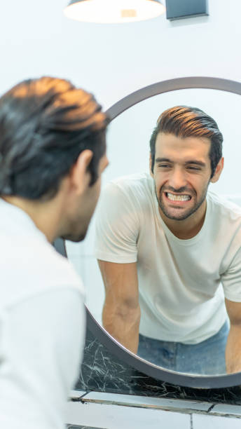 istock Man with toothbrush cleaning teeth and looking to mirror at home bathroom. 1491875476