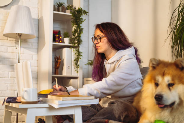 istock Woman with her dog sitting on the sofa, studying. 1491876919