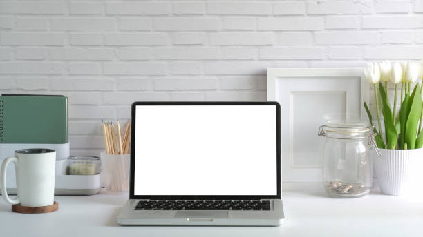 istock Front view of laptop computer, coffee cup and potted plant on white table. Empty screen for your advertise design. 1491878988