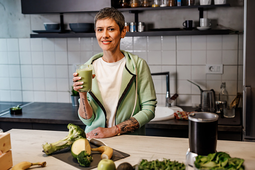 Mature  woman in the kitchen holding celery juice