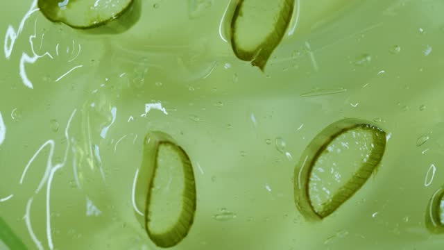 Close-up transparent green aloe gel with slices of aloe leaf
