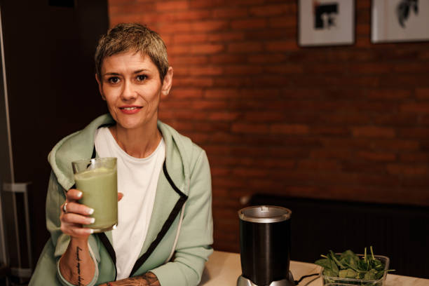 Mature  woman in the kitchen holding celery juice