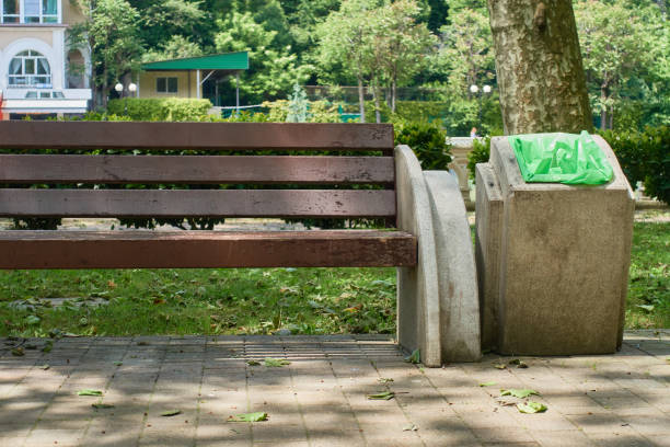 istock A wooden bench with a concrete railing sits on the sidewalk, next to a garbage can. 1491885716