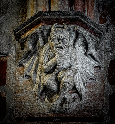 Medieval stone demon carved on the wall in the catholic church