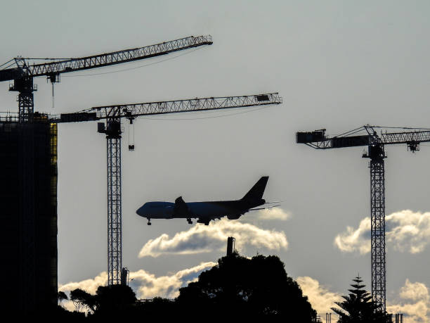 A United Parcel Service Boeing B747-8F, registration N617UP, is preparing to land on the east-west runway of Sydney Kingsford-Smith Airport, arriving from Honolulu.  The silhouette of a residential building and construction cranes complete the image.  This image was taken from Maroubra on a sunny and windy afternoon on 21 May 2023.