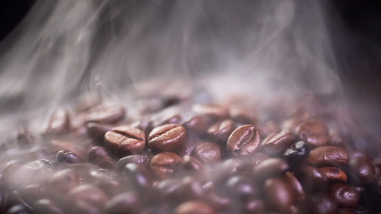 Coffee beans roasting with smoke,  selective focus, and soft focus.