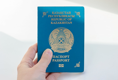 Person holds Kazakhstan travel passport in hand. Travel, tourism or immigration concept. Kazakstan kz citizenship. White background.