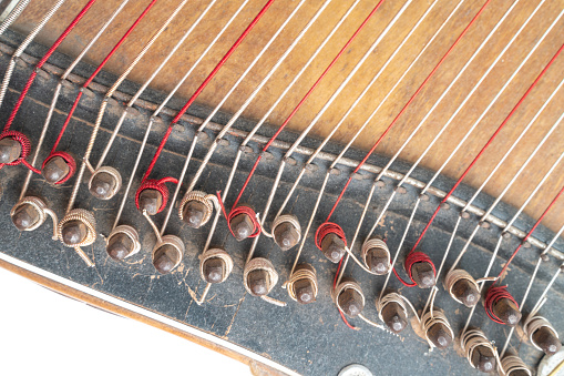 Top horizontal studio shot of vintage, old wooden zither isolated on white background. Detail of string pins. Dusty and scratched musical instrument
