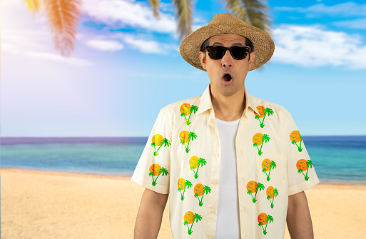 Latin man on vacation wearing floral shirt hat sunglasses at tropical beach afraid and shocked with surprise expression, fear and excited face.