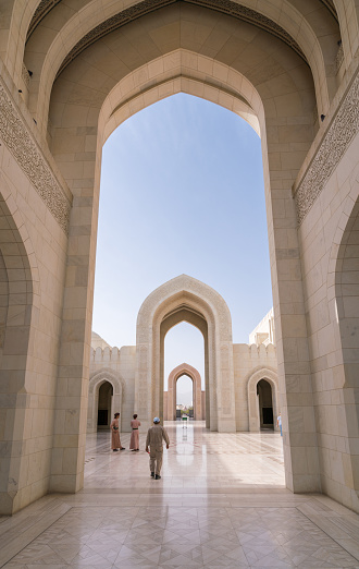Muscat, Oman - 04.04.2018: Tourists and guards walking in the courtyard of the Sultan Qaboos Grand Mosque, Muscat, Oman. Beautiful contemporary Arabian architecture