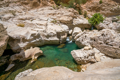Small narrow white stone gorge with turquoise waters in Wadi Bani Khalid, Oman. Beautiful natural swimming pool in Arabian desert