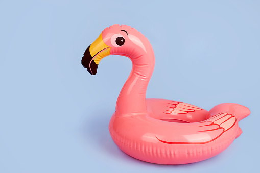 Inflatable flamingo on a blue background, a beach toy. Summer background with copy space.