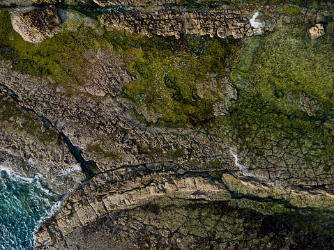 Aerial view of rocky beach and sea waves with diversities of nature elements, land and water with different colours
