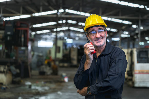 istock A mechanic, technician or senior foreman carries a walkie-talkie. Standing smart man smiling like an executive with the background being an industrial factory warehouse 1491977763