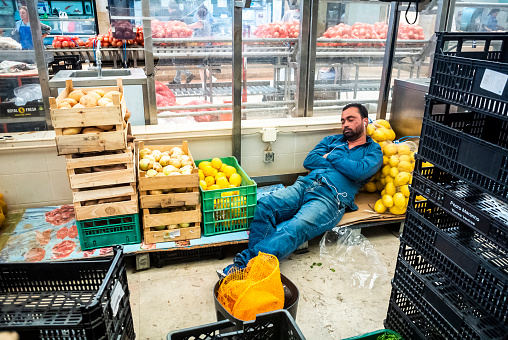 Lisbon, Portugal, Food Shop Worker sleeping inside Local Food Market, Time Out Market,