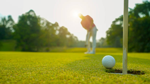 golfer putting ball auf dem grünen golf, linse flare auf sonne sonnenuntergang abendzeit. - golf golf club golf swing tee stock-fotos und bilder