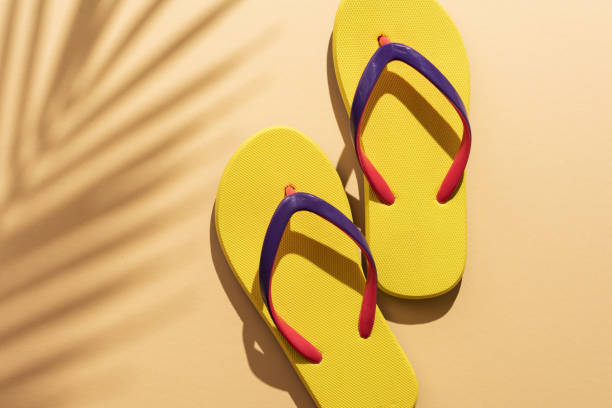 istock Yellow flip flops with a palm leaves shadow 1491986839