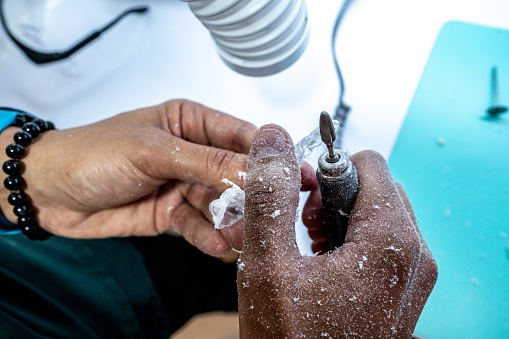 Dental assistant/technician using a mini sander on a denture mold at dentistry laboratory