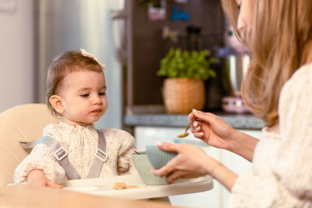 istock Young mom feeding her baby daughter with a spoon 1491990847
