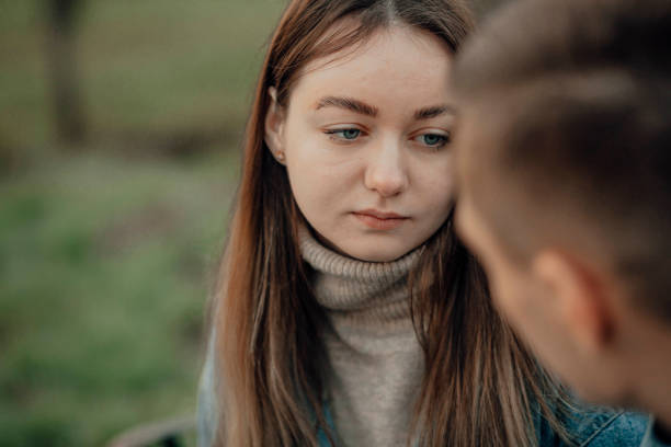Sad young woman looks at a man in the park, quarrel, question stock photo