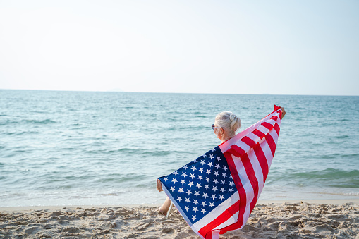 Woman holding US flag enjoying time at the beach.