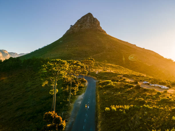 un par de hombres y mujeres viendo la puesta de sol en lion's head cerca de table mountain cape town - montaña de lions head fotografías e imágenes de stock