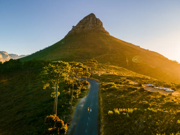 пара мужчин и женщин наблюдают за закатом в львиной голове возле столовой горы кейптауна - lions head mountain стоковые фото и изображения