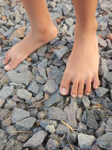 A boy standing barefoot on fine sharp gravel, foot massage. bare feet on gravel ground in the morning is very good for health. Nature massage