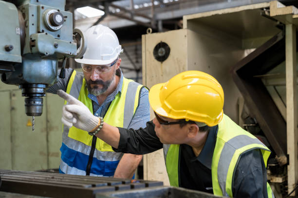 istock Staff or technicians are checking the operation of the old machine via the remote. Man worker in safety helmet working on steel machine. 1492016407