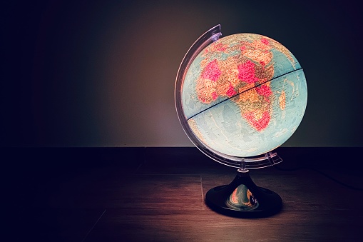 An illuminated globe seen in a dark room with a focus on Europe and Africa