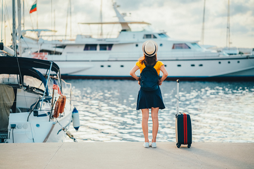 Rear view of tourist woman staring at the yachts before boarding