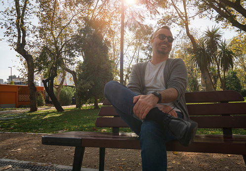 man relaxing sitting on a bench in a park