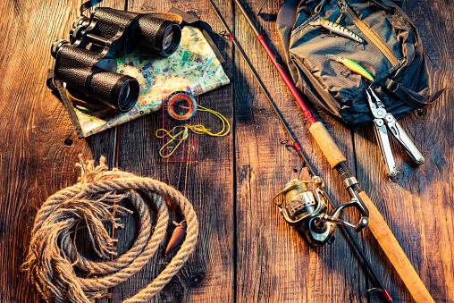 Fishing spinning with a reel line. Fishing items on a wooden background. Binoculars and rope.