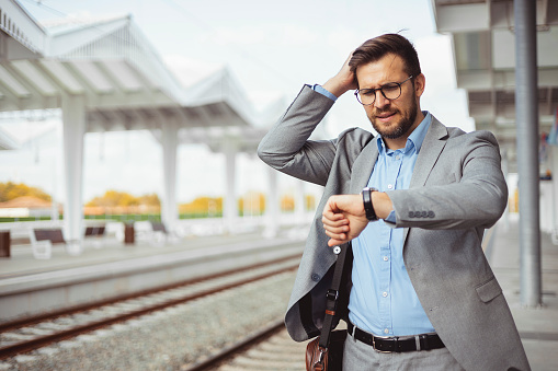 Anxious executive manager looking at his watch in train station
