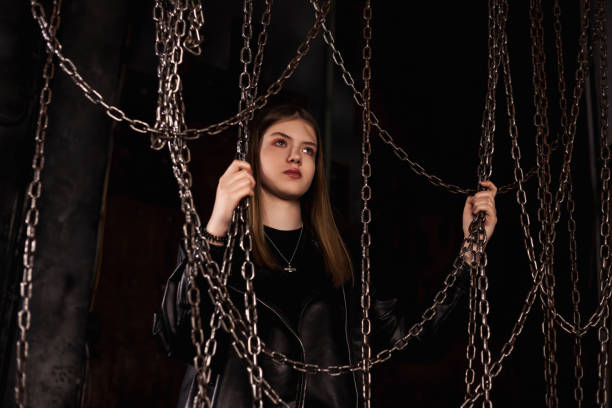 Lovely teen girl model 12-13 year posing in dark industrial room with chains, looking away. Cute classy teenage girl actress in leather jacket. Fashionable stylish image concept. Copy ad text space encantadora adolescente modelo 12-13 años posando en una habitación industrial oscura con cadenas, mirando hacia otro lado. linda y elegante actriz adolescente con chaqueta de cuero. concepto de imagen elegante de moda. copiar el espacio de texto del anu