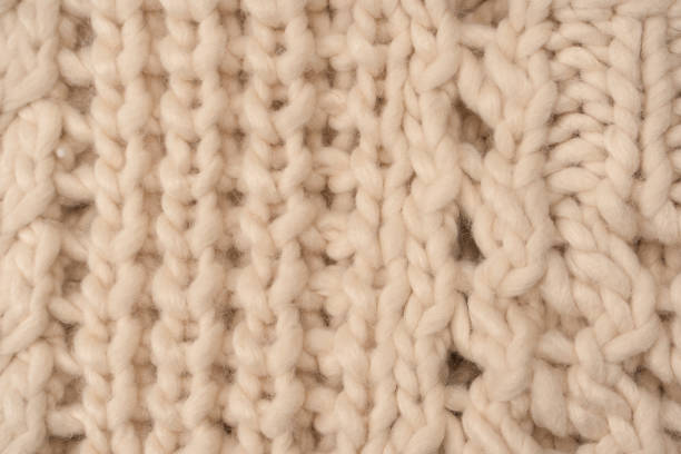 istock A fragment of beige knitted fabric, knitted from white sheep wool. 1492024463