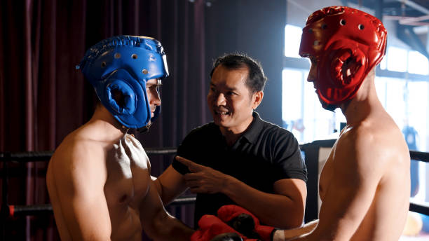 istock Close-up two boxers on red side, blue side are about fight, boxing referee arrested discuss rules boxing match, two them were fully equipped with protective equipment for injuries. 1492024563