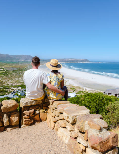Noordhoek beach along Chapman's peak drive Cape Town South Africa Beautiful white sand Noordhoek beach along Chapman's peak drive Cape Town South Africa. Noordhoek Beach Cape Town. Man and woman at the edge of a beach kommetjie stock pictures, royalty-free photos & images