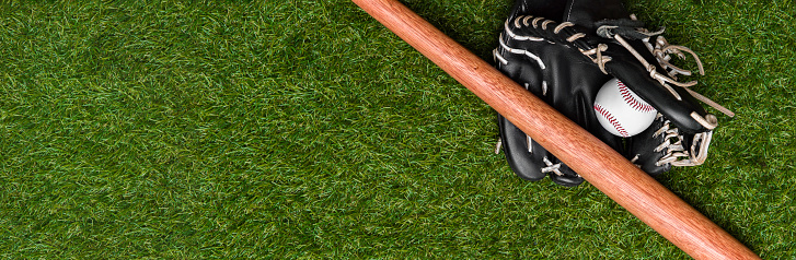 Bate de béisbol, guante y pelota en el campo de hierba verde. Fondo de tema deportivo con espacio de copia para texto y publicidad photo