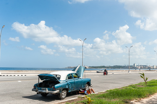 Havana, Cuba - October 23, 2017: Havana Cityscape and Man Repairing Old Car on the Street.