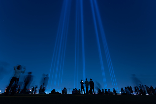 silhouette of people at night with the light show on the rooftop in Shibuya, Tokyo