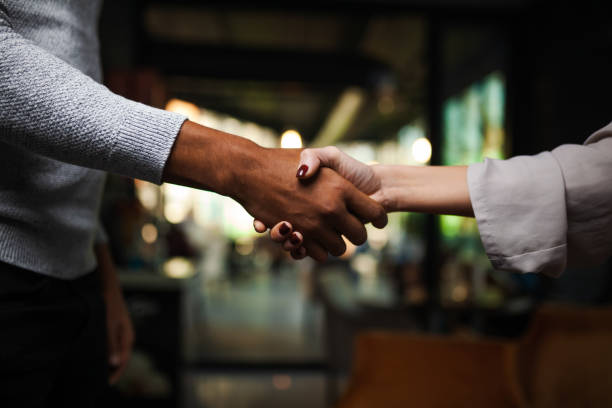 Two multiracial business colleagues working after work or during coffee break in a restaurant. Man and woman shaking hands after successful meeting.. stock photo