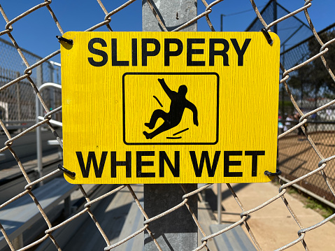 SLIPPERY WHEN WET sign on a fence