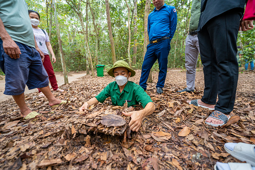 Ho Chi Minh city, Vietnam - 20 May 2023: A guide demonstrating how a Vietcong hide into the tunnel, Cu Chi tunnel is now touristic destination in Ho Chi Minh city, Vietnam
