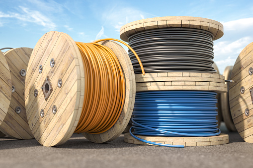 Wire electric cable of different colors on wooden coil or spool in warehouse.