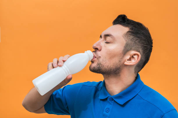 istock Handsome man drinks yogurt or milk on orange background. Mock up copy space 1492038617