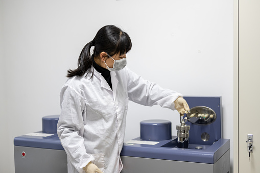 A female technician is conducting metal material testing using instruments in an industrial laboratory