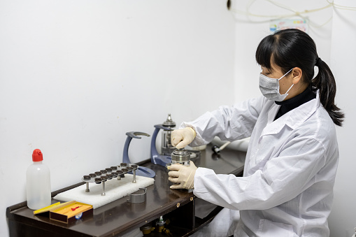 A female technician is conducting metal material testing using instruments in an industrial laboratory