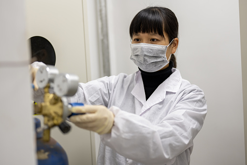 A female technician is conducting instrument safety testing in an industrial laboratory