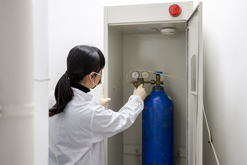 A female technician is conducting instrument safety testing in an industrial laboratory